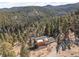 An aerial view of the wood home, showcasing its setting amidst lush greenery, a hillside and the scenic landscape at 10180 Blue Sky Trl, Conifer, CO 80433