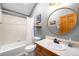 Well-lit bathroom with a shower and bath, updated fixtures, and a circular mirror at 10180 Blue Sky Trl, Conifer, CO 80433