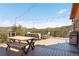 Spacious outdoor deck area with seating, dining table, and a built-in grill overlooking mountains at 10180 Blue Sky Trl, Conifer, CO 80433