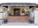 The Ambassador East entrance showcases brick steps, a black awning, and decorative potted plants at 130 N Pearl St # 304, Denver, CO 80203