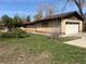 Side view of home with attached garage, brick exterior, green grass, and concrete walkway to the front at 5600 Dover St, Arvada, CO 80002
