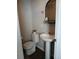 Powder room featuring a pedestal sink, toilet, and decorative mirror at 1078 Oak Cir, Denver, CO 80215