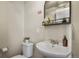 Powder room featuring a pedestal sink, toilet, and decorative mirror at 1078 Oak Cir, Denver, CO 80215