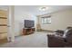 Cozy carpeted living room with a brown leather sofa, television, and natural light from the window at 11564 Green Ct, Conifer, CO 80433