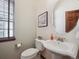 Updated powder room offers a pedestal sink, round mirror and wood floors at 5723 S Union Ct, Littleton, CO 80127