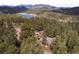 Overhead view of the property surrounded by tall trees and a lake in the distance at 27711 Moffat Rd, Evergreen, CO 80439