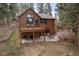 Backyard showing deck, stone patio, and lush landscaping around the house at 27711 Moffat Rd, Evergreen, CO 80439