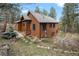 Exterior of beautiful home with unique roofline and surrounded by mature trees and landscaping at 27711 Moffat Rd, Evergreen, CO 80439