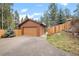 Garage and driveway area with a partial view of the house, fence, and trees at 27711 Moffat Rd, Evergreen, CO 80439
