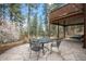 Outdoor patio with stone pavers, a dining table set, and natural views of the surrounding trees at 27711 Moffat Rd, Evergreen, CO 80439