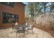 Stone patio with a dining table, lush trees, and stairs leading to the backyard of the house at 27711 Moffat Rd, Evergreen, CO 80439