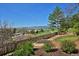 Landscaped backyard featuring a tiered garden, lush lawn, mature trees, and a walking path with mountain views at 810 Trail Ridge Dr, Louisville, CO 80027