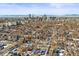 A winter aerial view captures a dense residential area with snow-covered roofs against the Denver skyline at 2336 N High St, Denver, CO 80205