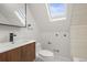 Bright bathroom featuring a wood vanity, modern faucet, skylight, and neutral color scheme at 2336 N High St, Denver, CO 80205