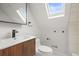 Bright bathroom with a skylight, wooden vanity, and contemporary fixtures at 2336 N High St, Denver, CO 80205