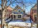 A two-story home with intricate architectural details and a charming front porch is shown with a swing near the sidewalk at 2336 N High St, Denver, CO 80205