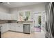 Kitchen with white cabinets, stainless steel dishwasher, tile backsplash, and doorway to back patio at 2336 N High St, Denver, CO 80205