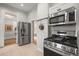 Modern kitchen with stainless steel appliances including refrigerator, stove, and microwave with a tile floor at 2336 N High St, Denver, CO 80205
