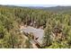 Scenic aerial view of a house nestled in a lush forest, surrounded by tall green trees and mountain views at 510 Hill Dr, Sedalia, CO 80135