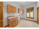 A light-filled laundry room with wooden cabinets, a utility sink, and a large window overlooking a yard at 510 Hill Dr, Sedalia, CO 80135