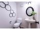Stylish powder room with round mirror, pedestal sink, and unique circular wall art creates a modern, inviting space at 6420 E Bates Ave, Denver, CO 80222