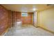 Unfinished basement featuring brick accent wall, window, and concrete floors, ready for customization at 4720 Perry St, Denver, CO 80212