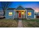 Charming home featuring a red front door, covered porch, and well-maintained lawn at dusk at 4720 Perry St, Denver, CO 80212