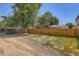 View of the backyard featuring a spacious grassy area, partial privacy fence, and mature trees at 3645 S Fox St, Englewood, CO 80110