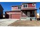 Two-story home featuring a two-car garage, covered porch with brick accents, and a traditional front door at 747 Sunflower Dr, Brighton, CO 80601