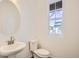 Clean powder room featuring a pedestal sink, toilet, and a bright window at 747 Sunflower Dr, Brighton, CO 80601