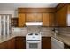 Kitchen featuring an electric stove, granite countertops, and wood cabinets at 1288 S Drexel Way, Lakewood, CO 80232