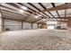 Large dirt floor indoor riding arena with metal rafters and natural light streaming through skylights at 28505 County Road 5, Elizabeth, CO 80107