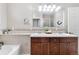 Bathroom featuring dual sinks, tan and white tile backsplash, and a white tub at 7996 Bradburn Blvd, Westminster, CO 80030