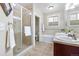 Bathroom with tan tile, glass shower, tub and dual sinks at 7996 Bradburn Blvd, Westminster, CO 80030