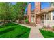 A lovely exterior view of a two-story townhome featuring brick chimney and lush green lawn and mature trees at 14093 E Radcliff Cir, Aurora, CO 80015