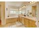 Bright bathroom featuring a soaking tub, dual vanities, and tiled floors at 17613 E Peakview Ave, Aurora, CO 80016
