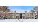 Charming condo complex with stone accents and balconies, surrounded by mature trees and snow-covered landscape at 4400 S Quebec St # 108L, Denver, CO 80237