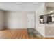 Hardwood floors lead to kitchen and front door from the living room with neutral walls and a pass-through kitchen window at 4400 S Quebec St # 108L, Denver, CO 80237