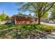Charming red brick home with a well-maintained front yard, shade tree, and sunny blue sky at 4953 W 61St Ave, Arvada, CO 80003