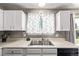 Efficient kitchen featuring white cabinets, a stainless steel sink, and practical workspace at 4416 E 93Rd Pl, Thornton, CO 80229