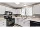 Well-lit kitchen with white cabinets, black appliances, and a stainless steel sink, perfect for cooking at 4416 E 93Rd Pl, Thornton, CO 80229