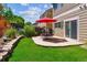 Landscaped backyard featuring a stone patio, outdoor seating, and a sliding glass door at 7342 S Mobile St, Aurora, CO 80016