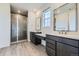 Modern bathroom with double vanity, large mirrors, quartz countertops, and glass enclosed tiled shower at 630 Sunrise St, Erie, CO 80516