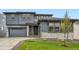 Charming two-story home with gray siding, stone accents, manicured lawn, and attached two car garage at 630 Sunrise St, Erie, CO 80516