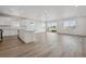 Open-concept kitchen and living room boasts abundant natural light and modern wood-look flooring throughout at 240 Lark Sparrow Way, Bennett, CO 80102