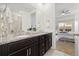 Bathroom featuring a double vanity with granite countertop and a view into the bedroom at 16249 Lanceleaf Pl, Parker, CO 80134