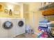 Bright laundry room equipped with modern washer and dryer units, storage shelves, and a decorative rug at 482 Southpark Rd, Highlands Ranch, CO 80126