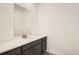 Well-lit half-bathroom with modern vanity featuring a gray cabinet, white countertop, and large mirror at 641 Sunrise St, Erie, CO 80516