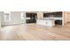 Open-concept kitchen featuring dark cabinets, a white island, stainless steel appliances, and wood-look flooring at 641 Sunrise St, Erie, CO 80516