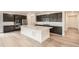 Modern kitchen with dark cabinets, stainless steel appliances, a large white island, and wood flooring at 641 Sunrise St, Erie, CO 80516
